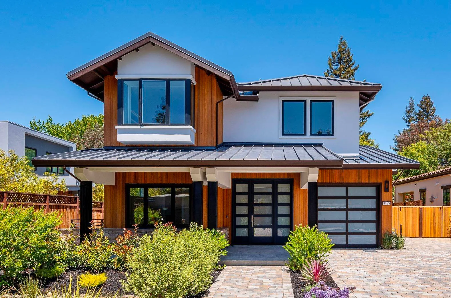 Custom home with cedar siding, white stucco, a standing-seam metal roof, and black-framed glass.