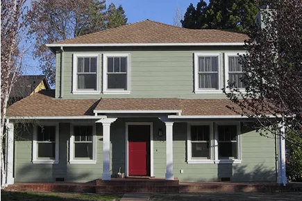 Two-story exterior with a columned porch, lap siding, and a red front door.